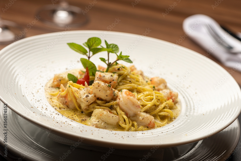 Shrimp creamy italian pasta on plate and wooden table