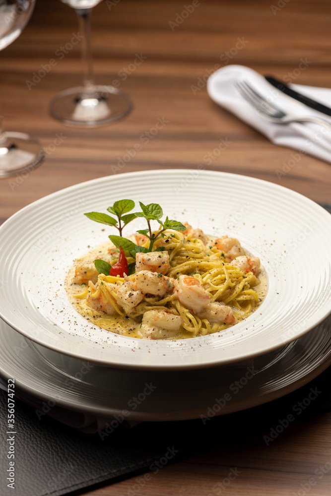 Shrimp creamy italian pasta on plate and wooden table Shrimp creamy italian pasta on plate and wooden table