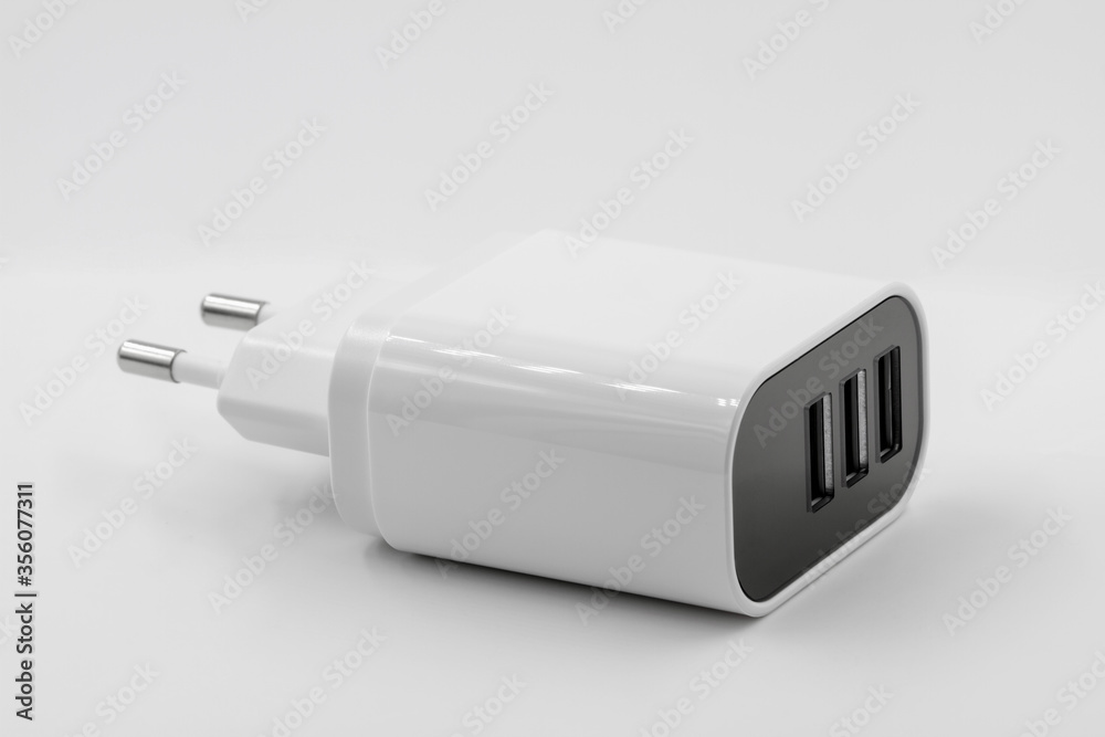 White socket travel charger for three USB ports output. USB electronics device charger on white background. Closeup. White socket travel charger for three USB ports output. USB electronics device charger on white background. Closeup.