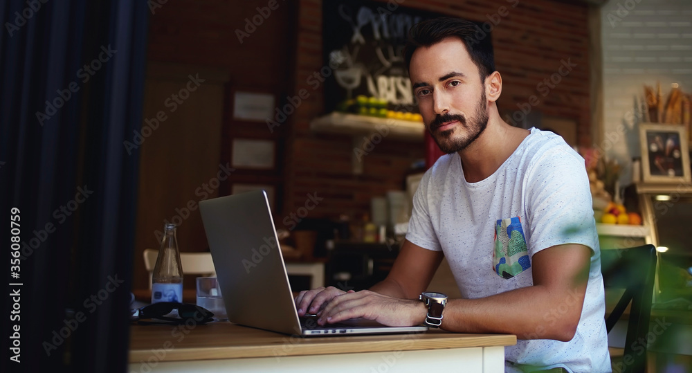 handsome man reading text message during work on net-book in comfortable coffee shop handsome man reading text message during work on net-book in comfortable coffee shop