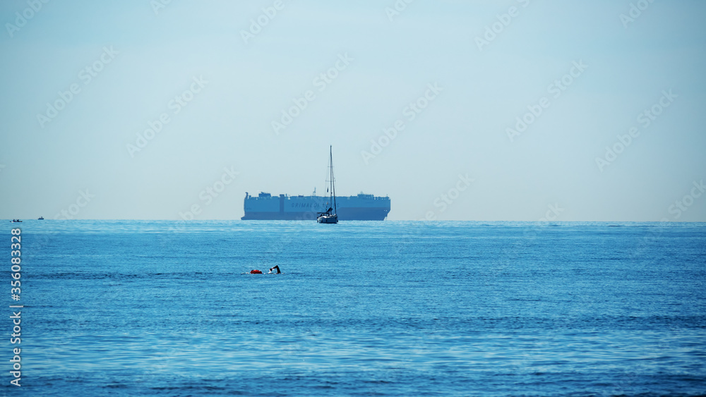 a container ship boat swimmer and  blue sea