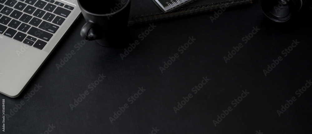 Top view of dark office desk with copy space, laptop, mug and schedule books Top view of dark office desk with copy space, laptop, mug and schedule books