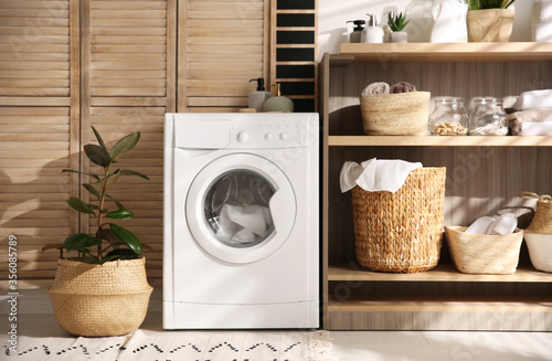 Modern washing machine and shelving unit in laundry room interior