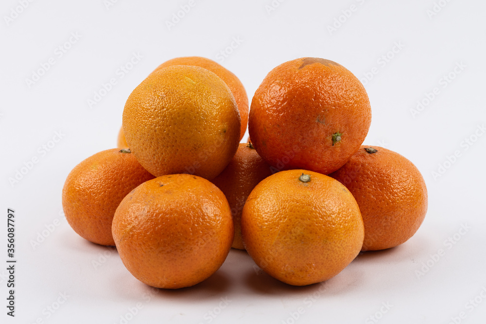Reife Orangen gestapelt auf hellem Untergrund Reife Orangen gestapelt auf hellem Untergrund