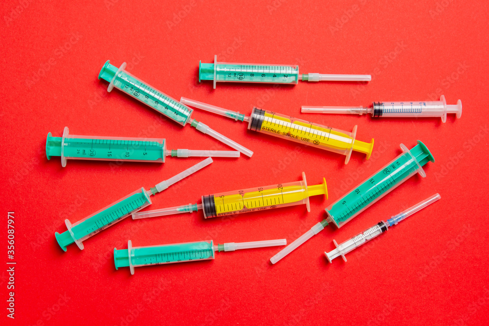 Top view of medical syringes with needles at red background with copy space. Injection treatment concept