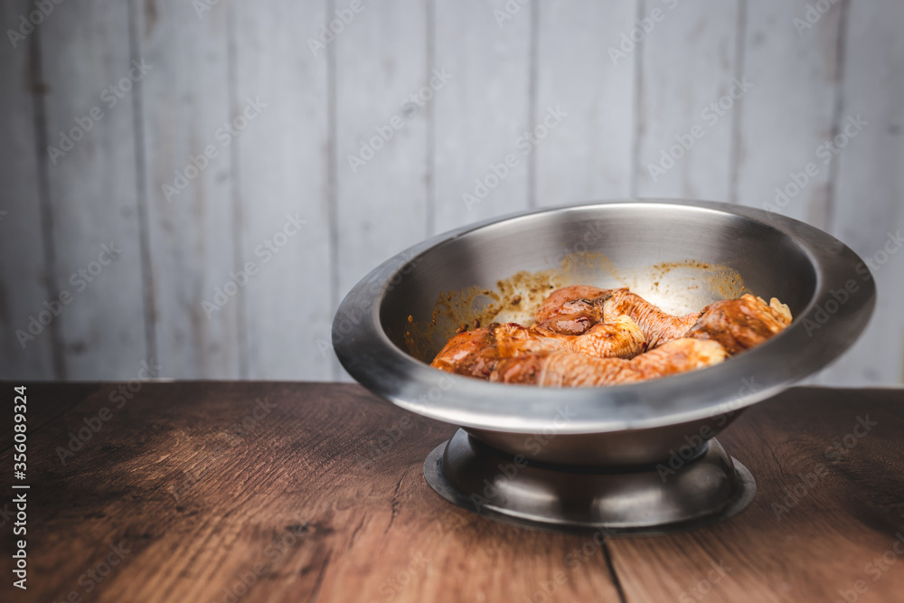 Close-up of a bowl full of marinated FRESH RAW ORGANIC CHICKEN DRUMSTICK with lots of spices on a dark brown wooden table. Close-up of a bowl full of marinated FRESH RAW ORGANIC CHICKEN DRUMSTICK with lots of spices on a dark brown wooden table.
