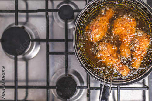 Frying Chicken in a pan full of oil. A pan with a frying basket. Concept of preparing Fried ORGANIC CHICKEN DRUMSTICK on the gas stove. photo