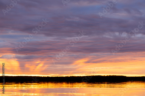 Water surface. Sunset sky background. Gold sunset sky with evening sky clouds over the lake. Small waves. Water reflection