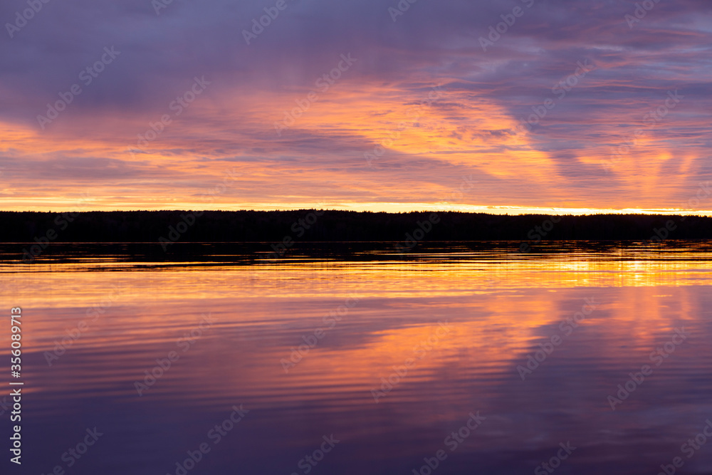 Water surface. Sunset sky background. Gold sunset sky with evening sky clouds over the lake. Small waves. Water reflection