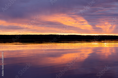 Water surface. Sunset sky background. Gold sunset sky with evening sky clouds over the lake. Small waves. Water reflection