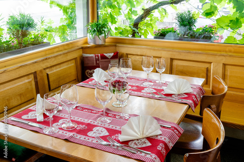 charming and inviting restaurnt table with a bay window and grapevines behind with colorful place settings photo