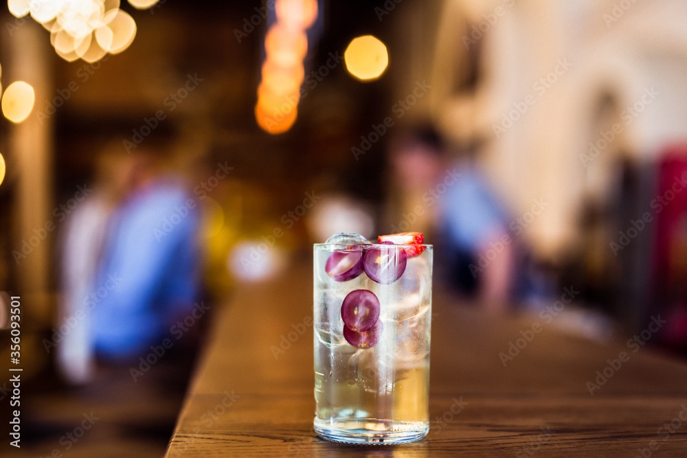 A refreshing iced long drink with grapes and strawberry at the bar