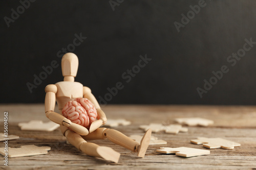 Toy man sits depressed with a puzzle. Despair and desolation. Confusion in itself, perplexity.