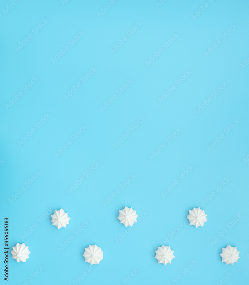 Naklejka premium Delicious white merengues on blue background. Happy day, breakfast, good morning concepts. Time for tea or coffee. Greeting or invitation card. Flat lay style with copy space.