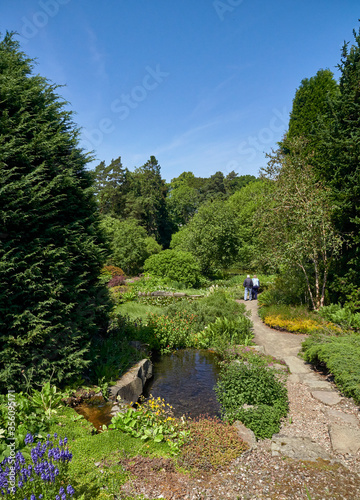An Elderly Couple walk down a path in the Rock Garden Area of St Andrews Botanic Gardens in Fife, Scotland.