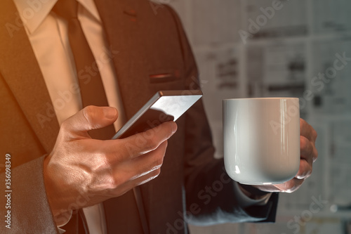 Businessman drinking coffee and using mobile phone in fake news infodemic concept photo