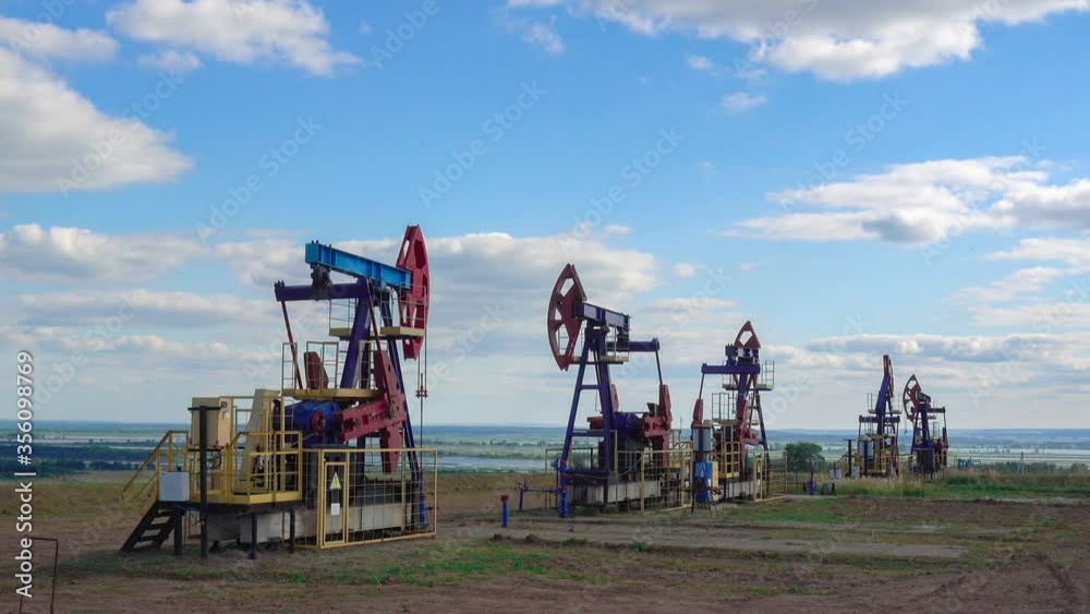 Oil pumps working on a field and stop. Metal oil derricks work, pumping oil and slowing it down. The oil crisis of 2020. The reduction of oil production Oil pumps working on a field and stop. Metal oil derricks work, pumping oil and slowing it down. The oil crisis of 2020. The reduction of oil production