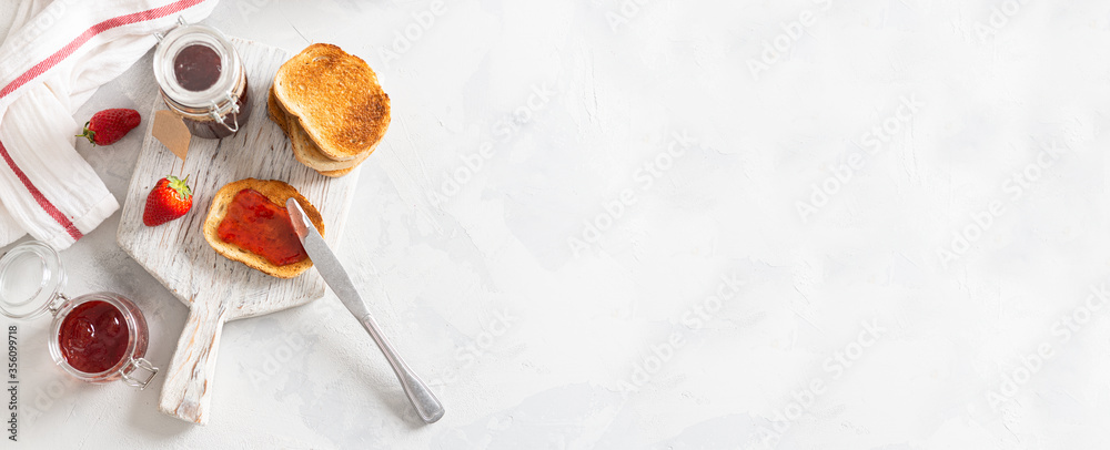 Fototapeta premium Fresh strawberry jam or confiture with crunchy toast for breakfast banner. Top view. Copy space for text. Natural organic food. Seasonal summer food. Banner for bakery or cafe