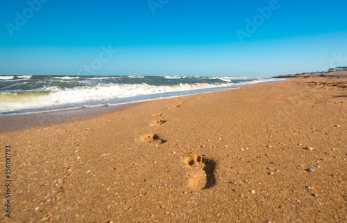 Footprints on wet sand leading to sea waves on a sunny warm summer day. The concept of the long-awaited vacation and vacation at sea. Copyspace