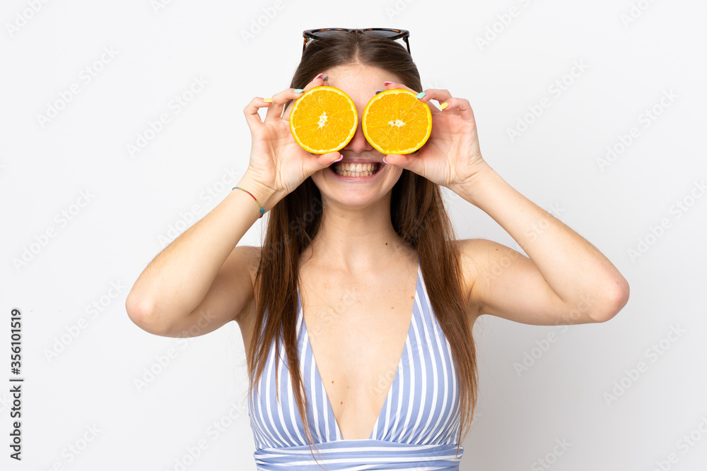 Young caucasian woman isolated on white background in swimsuit and holding an orange Young caucasian woman isolated on white background in swimsuit and holding an orange