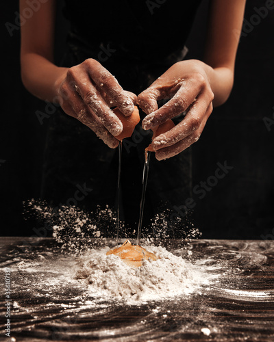 The cook broke the egg into flour. Close-up photo