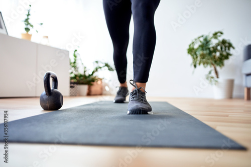 Closeup of female legs with sport shoes during home workout on sport mat