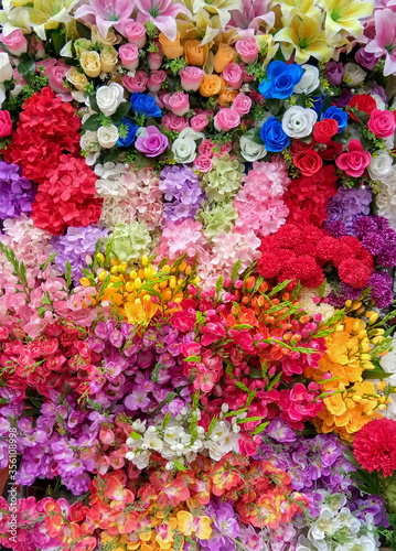 Colorful artificial flowers top view multicolor bouquet full frame, vertical picture, beautiful background for celebrate theme.