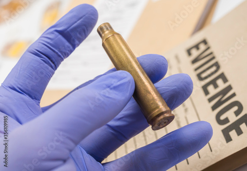 Scientific police picking up bullet in evidence bag, conceptual image