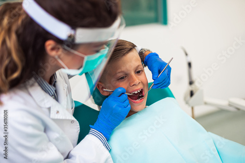 Cute little boy sitting on dental chair and having dental treatment.