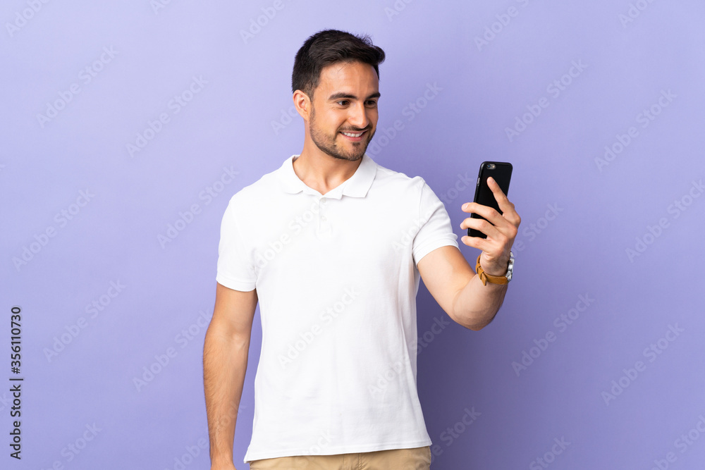 Young handsome man isolated on purple background making a selfie Young handsome man isolated on purple background making a selfie