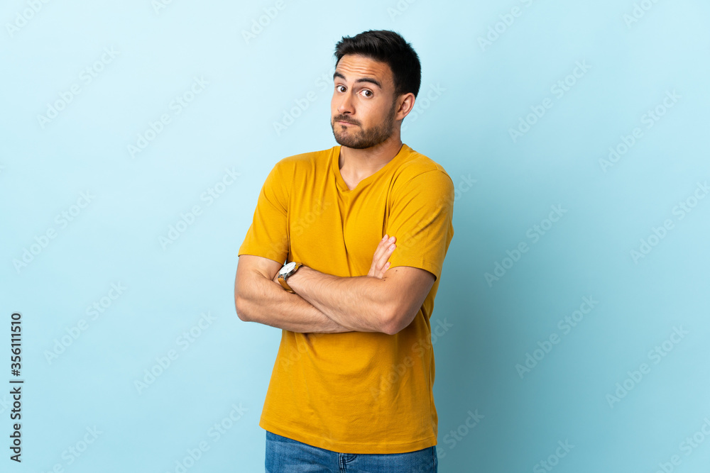 Young handsome man over isolated background making doubts gesture while lifting the shoulders Young handsome man over isolated background making doubts gesture while lifting the shoulders