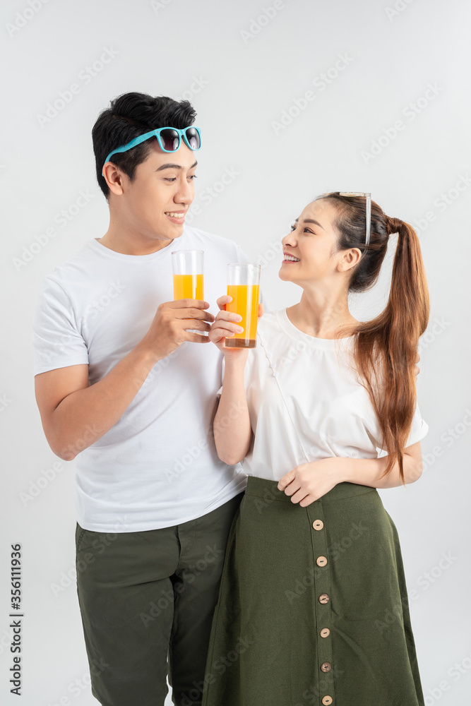 Happy young couple with glasses of orange juice isolated on a white background. Happy young couple with glasses of orange juice isolated on a white background.