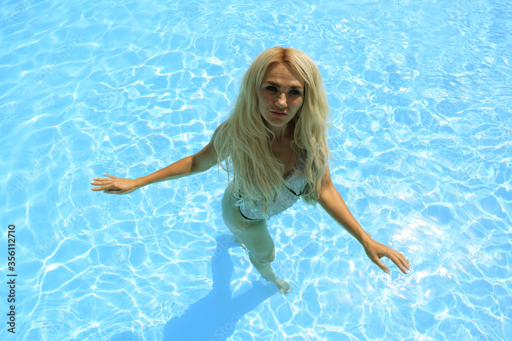 Top view of a blonde girl on a background of pool water