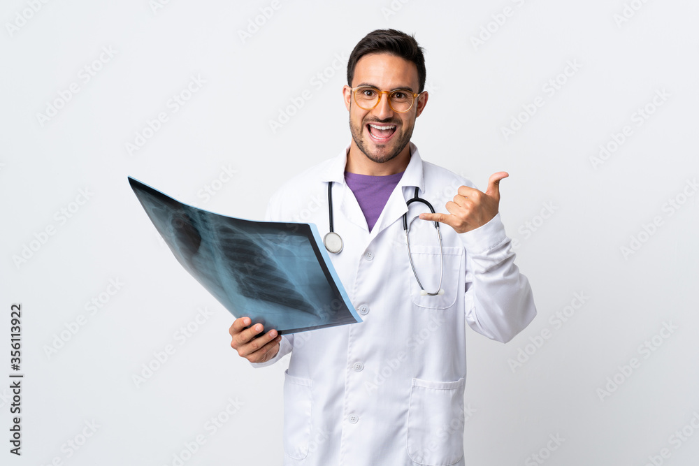 Young doctor man holding a radiography isolated on white background making phone gesture Young doctor man holding a radiography isolated on white background making phone gesture