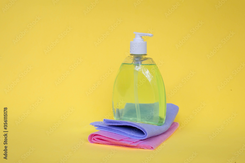pink and blue cleaning cloth, detergent on a yellow background. The concept of cleanliness and detergents pink and blue cleaning cloth, detergent on a yellow background. The concept of cleanliness and detergents
