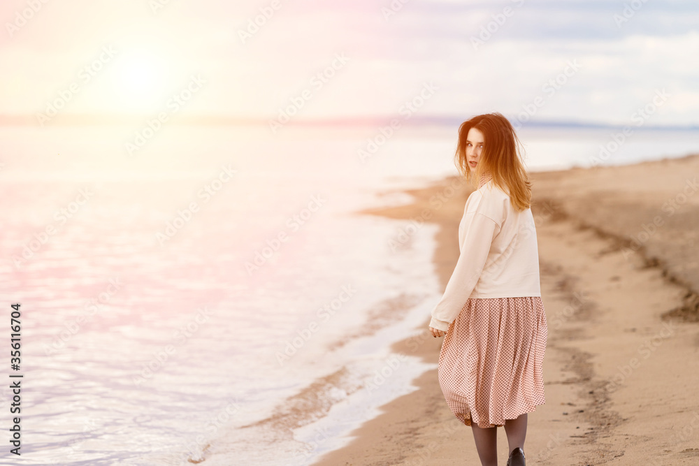 A young beautiful girl walks along the shore and looks back. A young beautiful girl walks along the shore and looks back.
