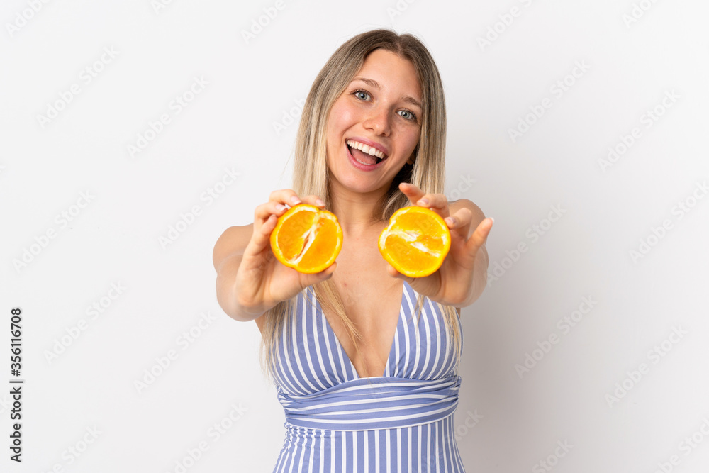 Young blonde woman isolated on white background in swimsuit and holding an orange Young blonde woman isolated on white background in swimsuit and holding an orange