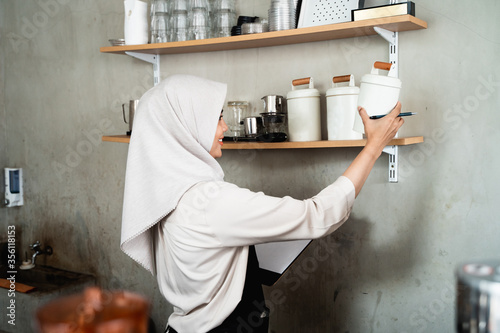 female waiter holds a bottle to check the stock of raw materials for the cafe photo