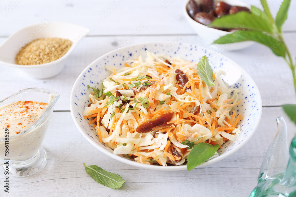 Coleslaw salad with carrots, dates and sauce for diet food, mint leaves dressing