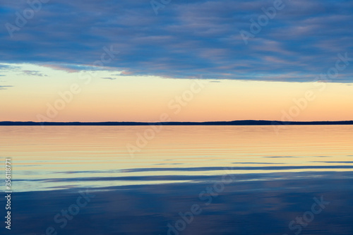 Water surface. View of a Sunset sky background. Dramatic gold sunset sky with evening sky clouds over the sea. View of a Crystal clear sea water texture. Landscape. Small waves. Water reflection © Aleksei