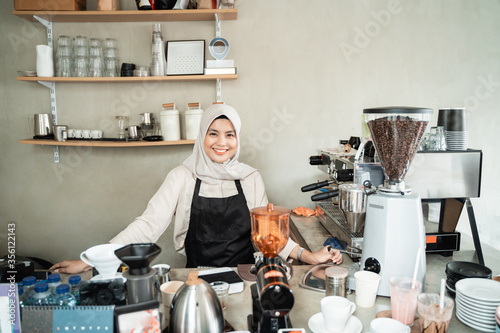 female barista smiling when stand on pub coffee shop of workplace