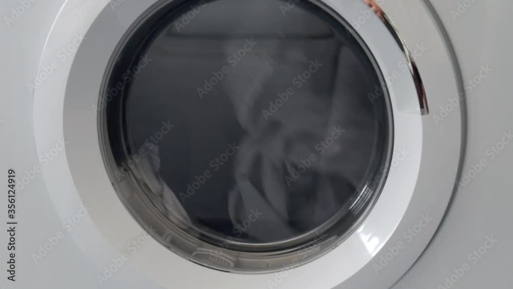 housework routine concept. clothes spinning inside a dryer laundry machine.