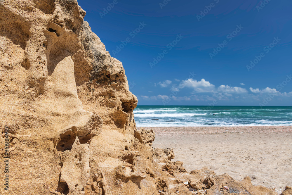 View of the turquoise waters of the Mediterranean Sea through sand formations on the shore against the blue sky