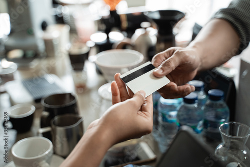 close up hand of the buyer gives a credit card to the seller to pay at the cafe