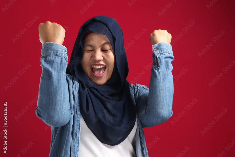Portrait of success beautiful muslim businesswoman wearing hijab screaming shouting and shows winning victory gesture Portrait of success beautiful muslim businesswoman wearing hijab screaming shouting and shows winning victory gesture