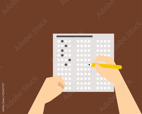Top view: Exam or education test concept. There are answer sheet and pencil in right hand on the desk. 