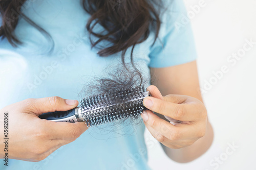 young woman worried about Hair loss problem, hormonal disbalance, stress concept. Many hair fall after combing in hair brush in hand. Female untangled her hair with a comb, Health care