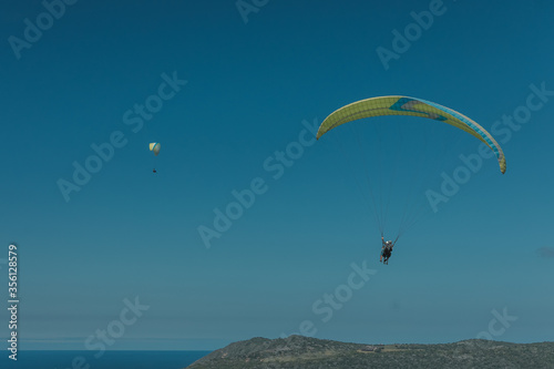Two paragliders are flying in the sky