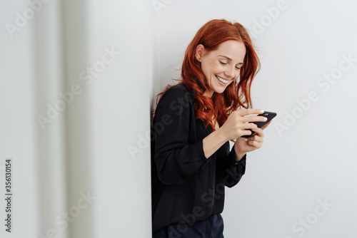 Young woman texting on mobile and smiling