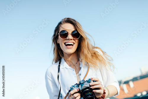 Happy young tourist smiling with sunglasses and camera